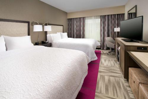 um quarto de hotel com duas camas e uma televisão de ecrã plano em Hampton Inn Louisville East Hurstbourne em Louisville