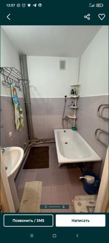 ein Badezimmer mit einem Waschbecken, einer Badewanne und einem WC in der Unterkunft Квартира in Tridtsatʼ Let Kazakhstana
