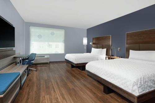a hotel room with two beds and a flat screen tv at Tru By Hilton Jacksonville St Johns Town Center in Jacksonville
