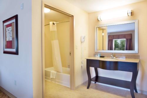 a bathroom with a sink and a mirror and a tub at Hampton Inn & Suites Laurel in Laurel