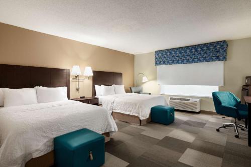 a hotel room with two beds and a chair at Hampton Inn & Suites Atlanta Airport West Camp Creek Pkwy in Atlanta