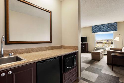 a bathroom with a sink and a mirror and a living room at Hampton Inn & Suites Atlanta Airport West Camp Creek Pkwy in Atlanta