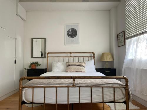 een slaapkamer met een bed met witte muren en een raam bij Cosy Shoreditch flat in Londen