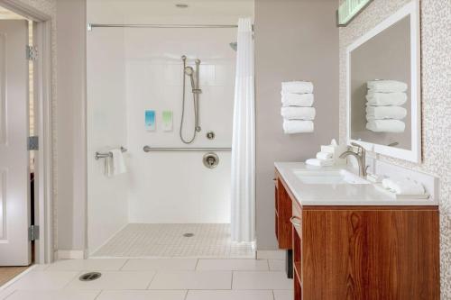 baño blanco con ducha y lavamanos en Home2 Suites by Hilton Fayetteville, NC, en Fayetteville