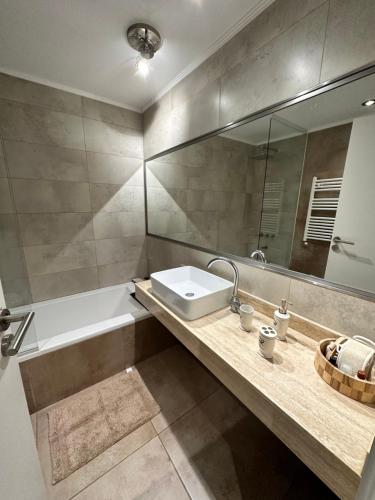 a bathroom with a sink and a tub and a mirror at Depto 3 amb zona Guemes con cochera, balcón a la calle con parrilla a gas in Mar del Plata