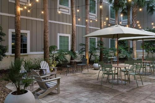 a patio with tables and chairs and an umbrella at Hampton Inn New Smyrna Beach in New Smyrna Beach