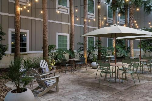 un patio con mesas, sillas y una sombrilla en Hampton Inn New Smyrna Beach en New Smyrna Beach