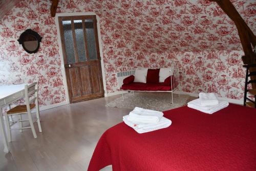 a room with a red bed and a red couch at Les Haltes du Clos du Petit Dannezy in Cour-Cheverny