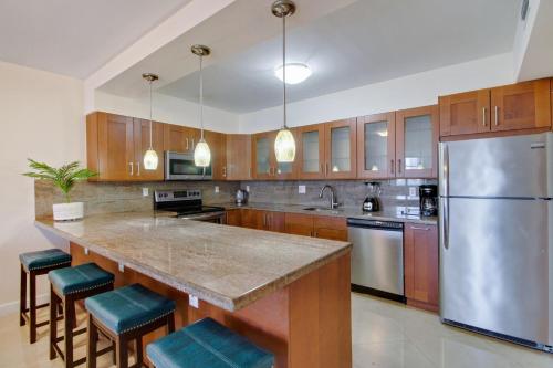 a large kitchen with a large island with blue stools at Family Beach Home w Ocean & Bay Views - Upgraded Corner Unit in Miami Beach