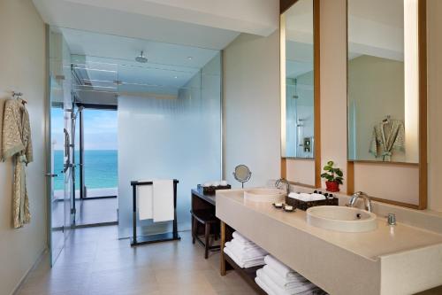 een badkamer met 2 wastafels en een grote spiegel bij Vana Belle, A Luxury Collection Resort, Koh Samui in Chaweng Noi Beach
