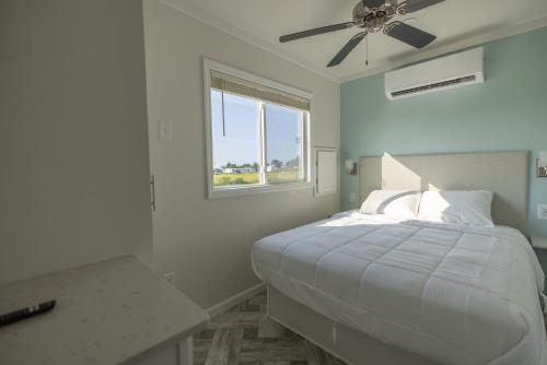 a white bedroom with a bed with a ceiling fan at Blufin Bungalows & Marina in Chincoteague