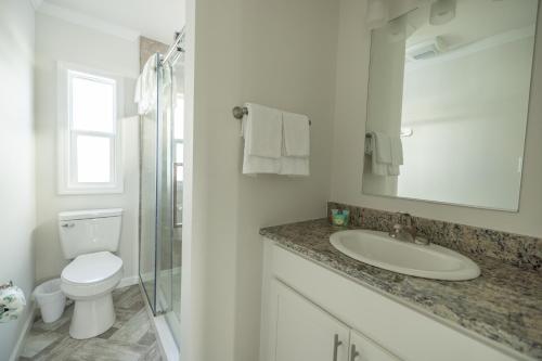 a white bathroom with a sink and a toilet at Blufin Bungalows & Marina in Chincoteague