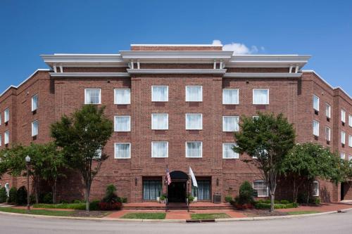 a red brick building with a flag in front of it at Homewood Suites by Hilton Huntsville-Village of Providence in Huntsville
