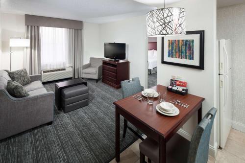 a living room with a table and a living room with a couch and a room at Homewood Suites by Hilton Huntsville-Village of Providence in Huntsville