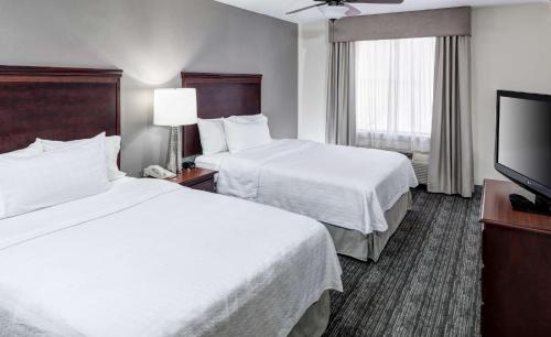 a hotel room with two beds and a flat screen tv at Homewood Suites by Hilton Huntsville-Village of Providence in Huntsville