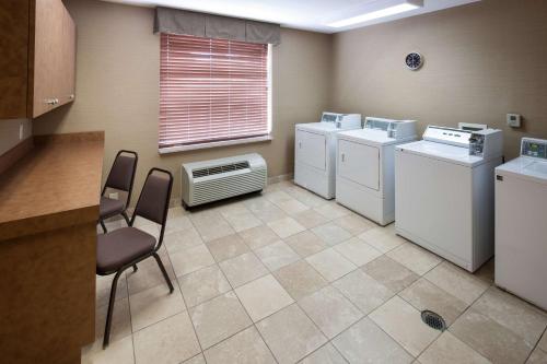 a laundry room with washing machines and a chair and a window at Homewood Suites by Hilton Huntsville-Village of Providence in Huntsville