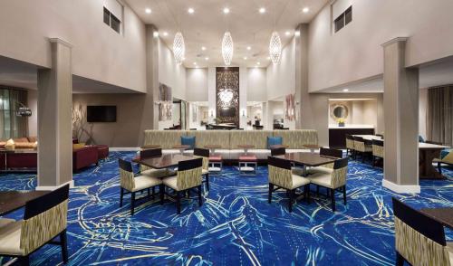 a hotel lobby with tables and chairs on a blue carpet at Homewood Suites by Hilton Cape Canaveral-Cocoa Beach in Cape Canaveral