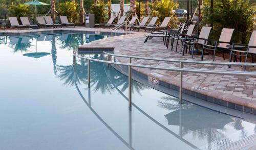 a swimming pool with chairs and a reflection in the water at Homewood Suites by Hilton Cape Canaveral-Cocoa Beach in Cape Canaveral
