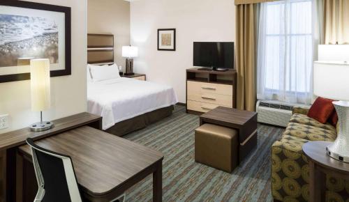 a hotel room with a bed and a desk and a couch at Homewood Suites by Hilton Cape Canaveral-Cocoa Beach in Cape Canaveral