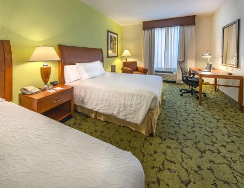 a hotel room with two beds and a desk at Hilton Garden Inn Tallahassee Central in Tallahassee