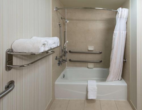 a bathroom with a tub and a shower with towels at Hilton Garden Inn Tallahassee Central in Tallahassee