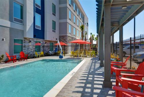 a swimming pool with chairs and tables and a building at Home2 Suites By Hilton Panama City Beach, Fl in Panama City Beach