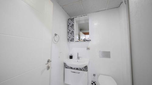 a white bathroom with a sink and a mirror at Duman Safir Rezidans in Kayseri