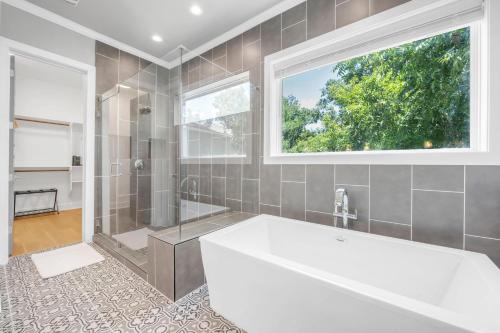 a bathroom with a tub and a shower and a window at Rolling Waves Haven Concierge Services Available in Kingsland