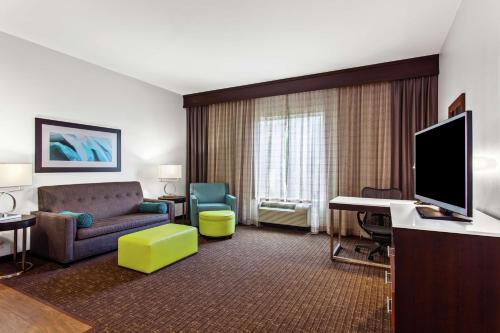 a living room with a couch and a television in a hotel room at Hilton Garden Inn Victoria in Victoria