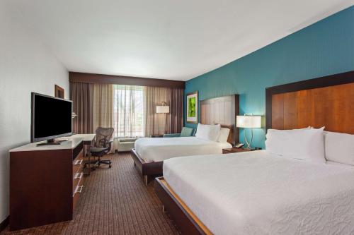 a hotel room with two beds and a flat screen tv at Hilton Garden Inn Victoria in Victoria