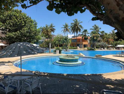 a large swimming pool with a fountain and an umbrella at Casa en Caribbean con Wifi in Tucacas