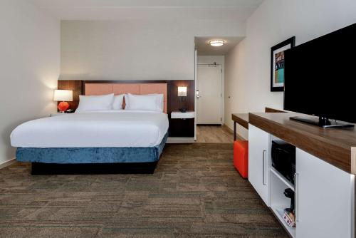 a hotel room with a bed and a flat screen tv at Hampton Inn Baltimore Bayview Campus in Baltimore