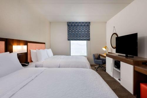 a hotel room with two beds and a flat screen tv at Hampton Inn Baltimore Bayview Campus in Baltimore