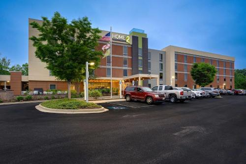 un grand bâtiment avec des voitures garées dans un parking dans l'établissement Home2 Suites by Hilton Lexington Park Patuxent River NAS, MD, à Lexington Park