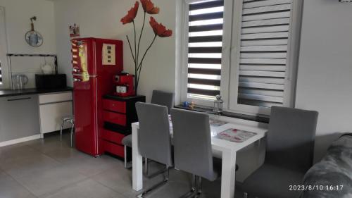 uma cozinha com uma mesa e cadeiras brancas e um frigorífico vermelho em Domek ZOZO nad jeziorem w Okuniowcu em Suwałki