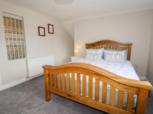 a bedroom with a wooden bed with white sheets and pillows at 4 Bodnant Road in Colwyn Bay