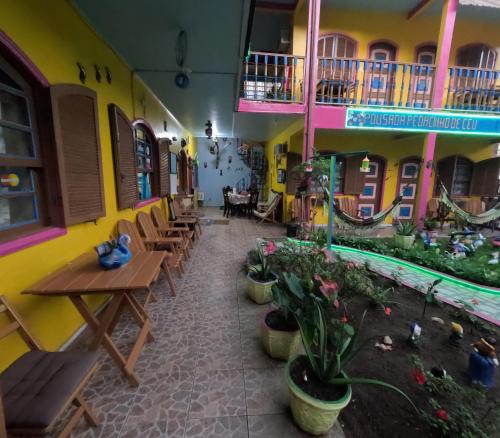 an empty restaurant with tables and chairs and plants at Pousada Pedacinho de Céu in Abraão