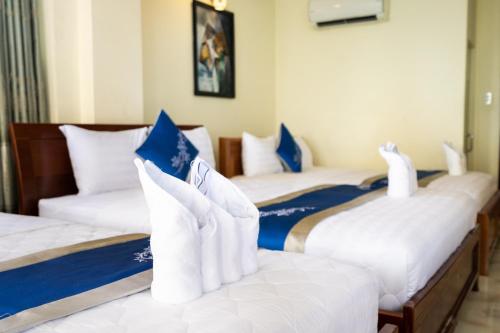 a room with three beds with blue and white pillows at Mai Phương - RUBY SAIGON HOTEL in Ho Chi Minh City