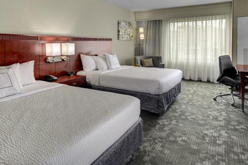 a hotel room with two beds and a desk at Courtyard by Marriott Anniston Oxford in Oxford