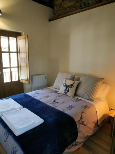 a bedroom with a bed with a blue blanket on it at Studio Rural in Vilarinho