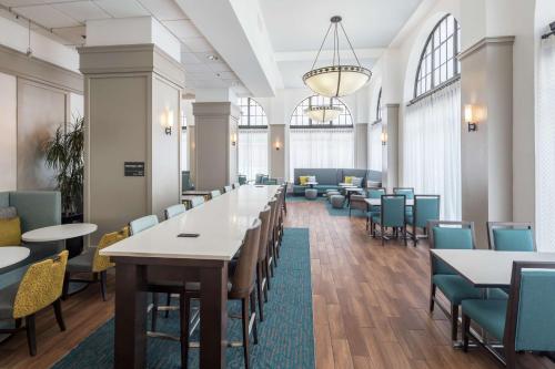 Hampton Inn & Suites Atlanta-Downtown في أتلانتا: غرفة كبيرة بها طاولات وكراسي ونوافذ