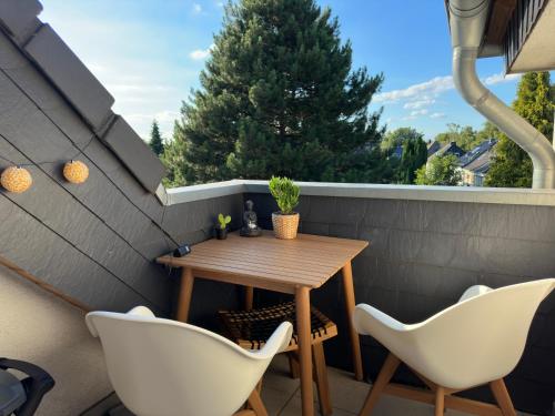 un pequeño patio con mesa de madera y sillas blancas en Möbliert-nahe Bochumer Ruhrstadion-WLAN-Netflix-Loggia en Bochum