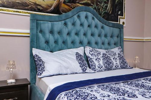 a bed with a blue head board and pillows at Hôtel The Place in Yaoundé