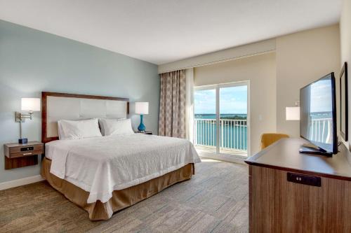 クリアウォーター・ビーチにあるHampton Inn and Suites Clearwater Beachのベッドルーム(ベッド1台、テレビ、バルコニー付)
