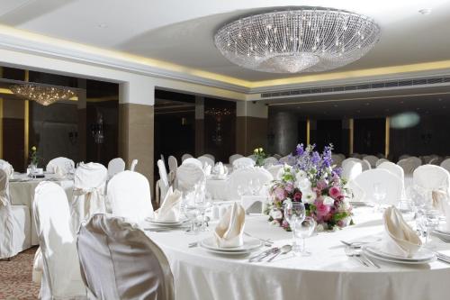 a banquet hall with white tables and chairs and a chandelier at Lancaster Suites Raouche in Beirut