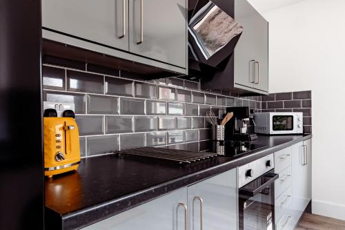 a kitchen with white cabinets and a black counter top at Brown Ball in Barrow in Furness