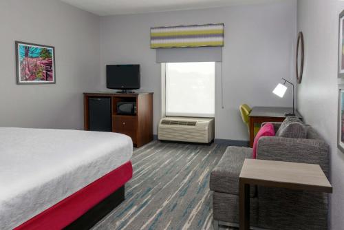 a hotel room with a bed and a couch and a tv at Hampton Inn & Suites Winston-Salem/University Area in Winston-Salem