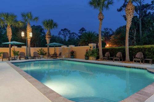 a pool with chairs and palm trees at night at Hilton Garden Inn Jacksonville/Ponte Vedra in Ponte Vedra Beach