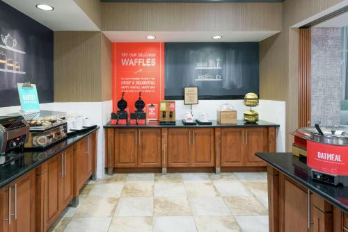 a large kitchen with wooden cabinets in a restaurant at Hampton Inn & Suites Orlando Airport at Gateway Village in Orlando