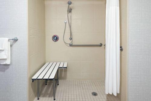 a shower with a bench in a bathroom at Hampton Inn & Suites Orlando Airport at Gateway Village in Orlando